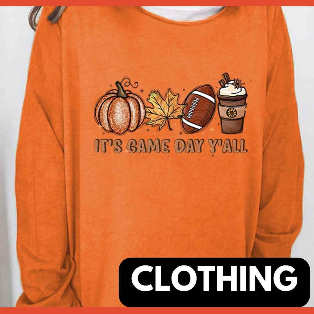 A woman wearing an orange long sleeve sweatshirt with the images of a pumpkin, fall leaf, football, a coffee latte and the words "it's game day y'all" on the shirt. The words "CLOTHING" in bold.