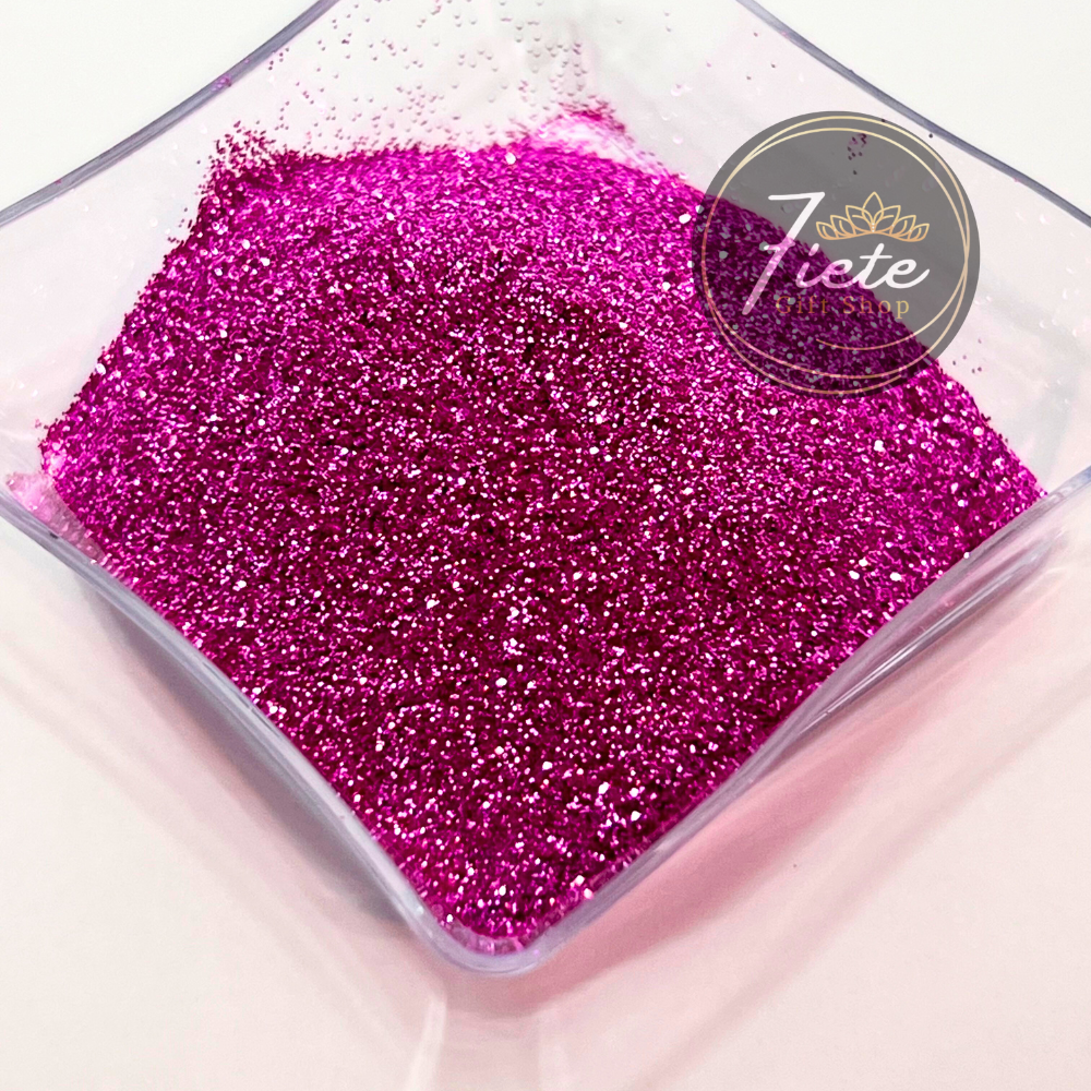 Top view of a square clear tray full of pink ultra fine metallic glitter.