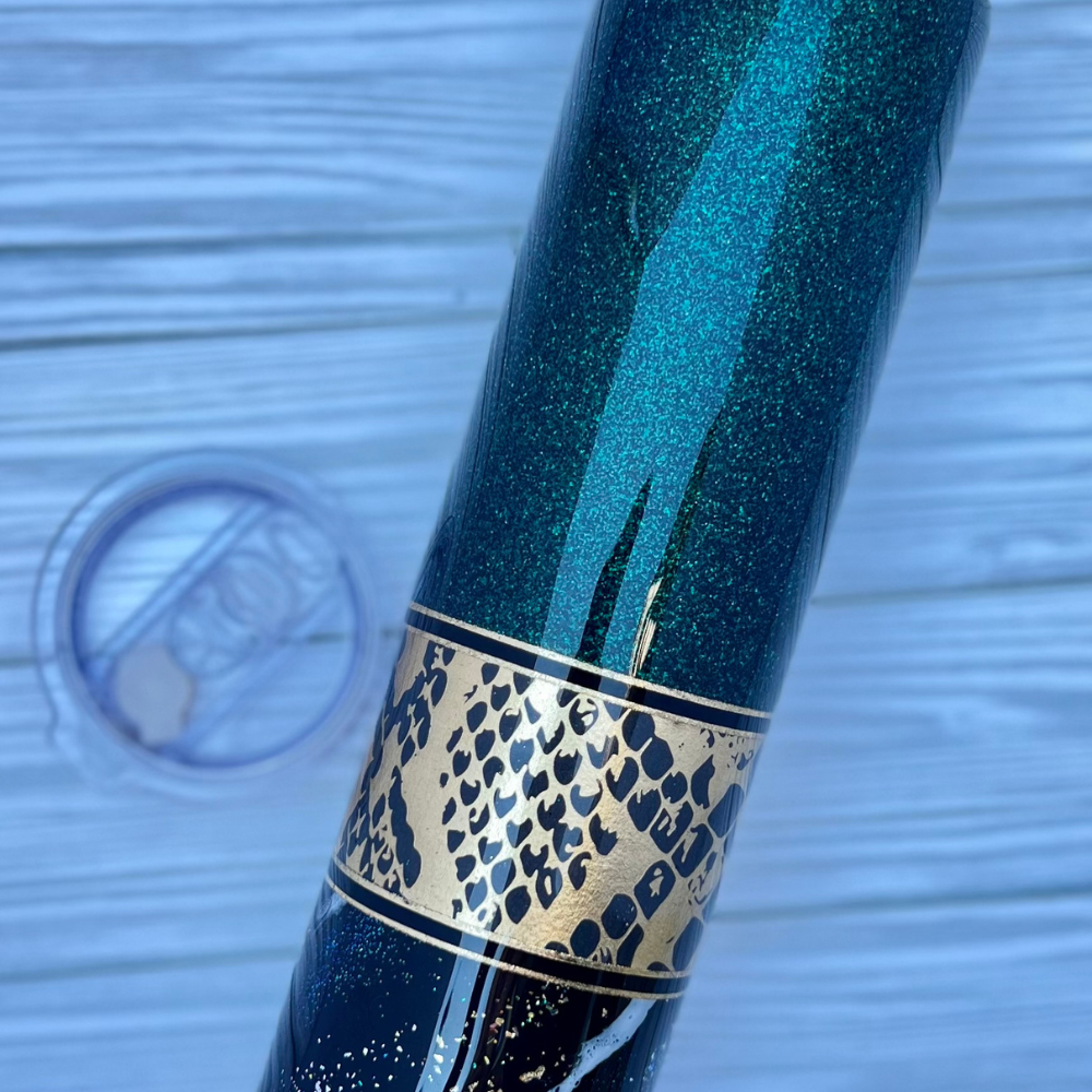 The tumbler lying flat showing the top half of the tumbler which is the deep emerald green glitter.