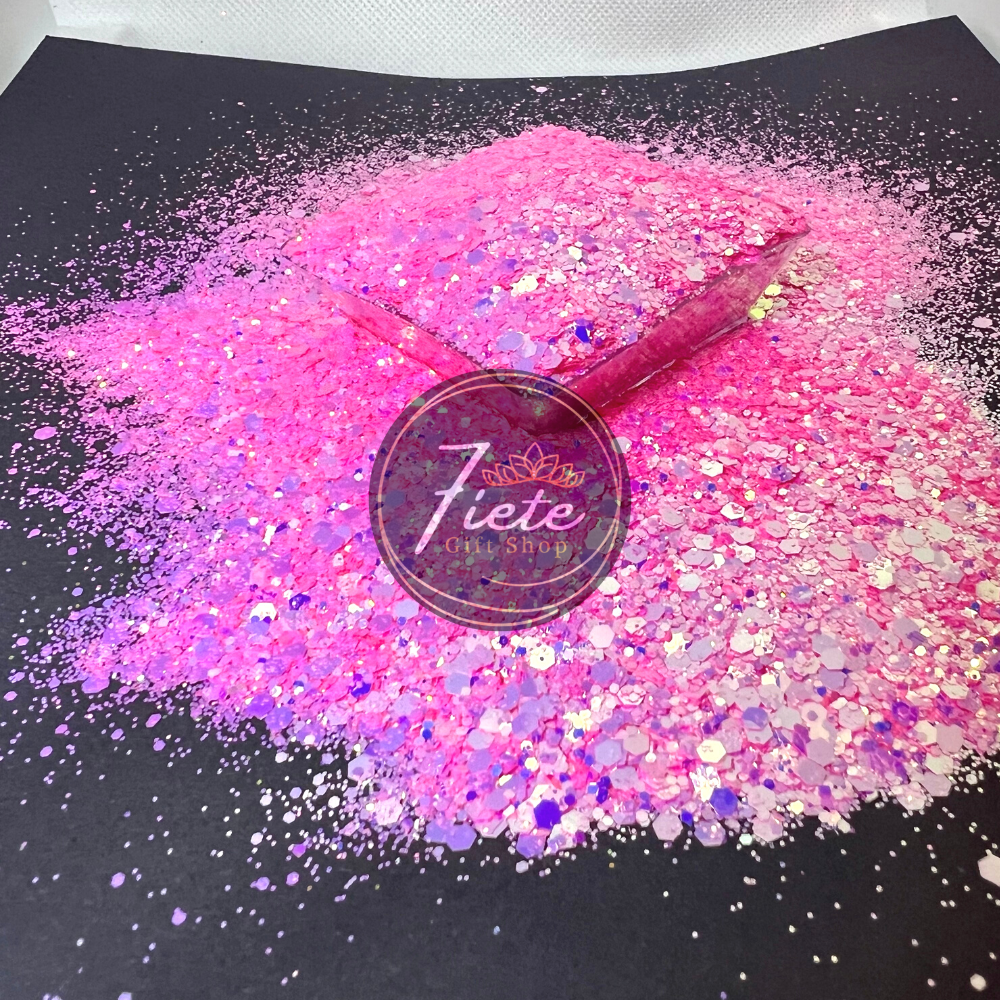 Glitter overflowing onto a black flat surface. The glitter is neon pink color changing into purples.