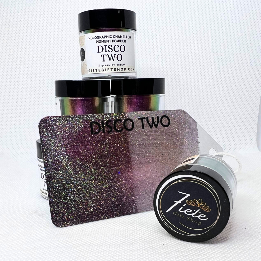 The words "DISCO TWO HOLO CHAMELEON" in bold black letters, and open container of the pigments a metal gift tag displaying when used on light and dark background showcasing the holographic affect. This view shows off dark pink/dark purple colors.