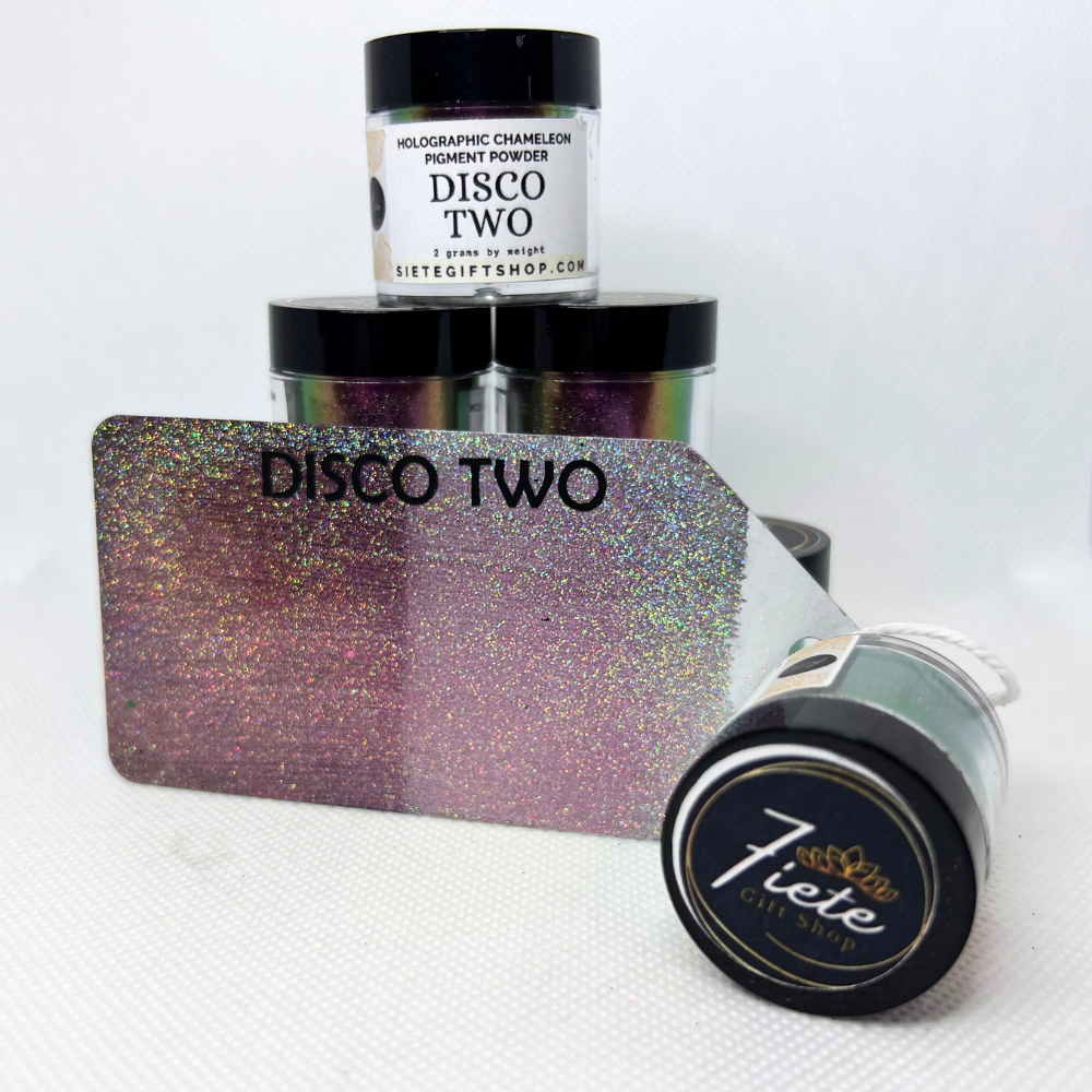 The words "DISCO TWO HOLO CHAMELEON" in bold black letters, and open container of the pigments a metal gift tag displaying when used on light and dark background showcasing the holographic affect. This view shows off dark pink/dark purple colors.