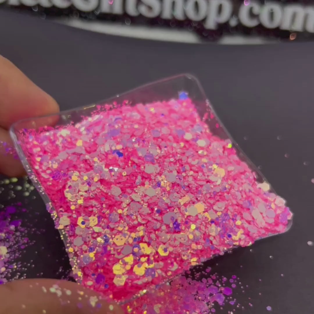 A womans hand moving a small tray side to side of the pink/purple glitter.